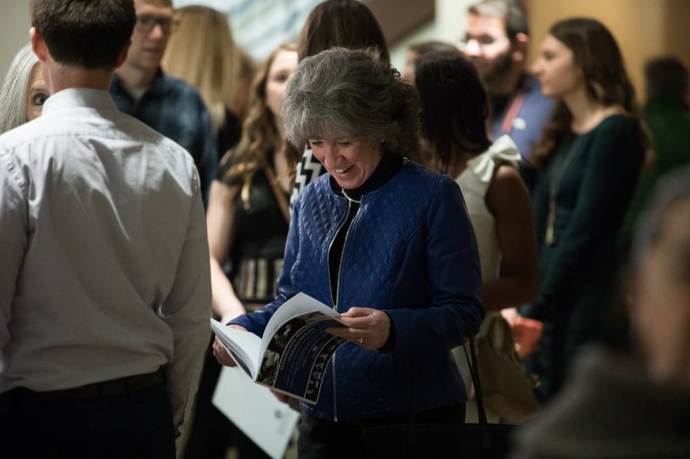 Woman smiling as she looks through the Fall 2019 Graduate Student Celebration program